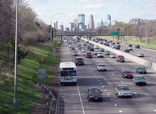 BUS-ONLY SHOULDER LANE on I-35W south of downtown Minneapolis. Modern transit buses measure 8.5 feet (2.59 meters) across the track, and approximately 9.5 feet (2.90 meters) across the rear-view mirrors. Typical bus-only shoulder lanes are 10 feet (3.08 meters) wide, leaving small margin for driver error.
