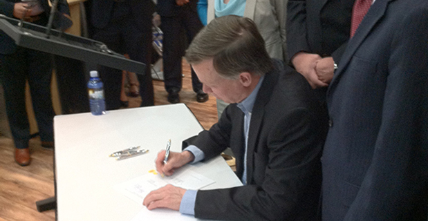 Colorado Governor John Hickenlooper signs a space-friendly bill at the 30th Space Symposium in Colorado Springs.