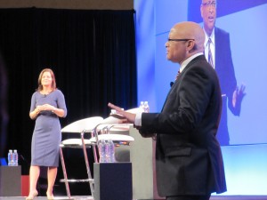 CTIA President Meredith Atwell Baker laughs as The Daily Show's Larry Wilmore provides news updates between opening keynotes.