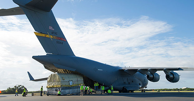 A quality assurance team from the 45th Launch Group off-loads a GPS IIF-12 satellite from a C-17 Globemaster III on Cape Canaveral Air Force Station, Fla., Oct. 8. A crowd from the government and industry partnership, who will complete the satellite’s final assembly, gathered on the Cape’s “Skid Strip” to watch the off-loading of the satellite they will prepare to launch aboard a United Launch Alliance rocket in 2016. (U.S. Air Force photo/James Rainier)
