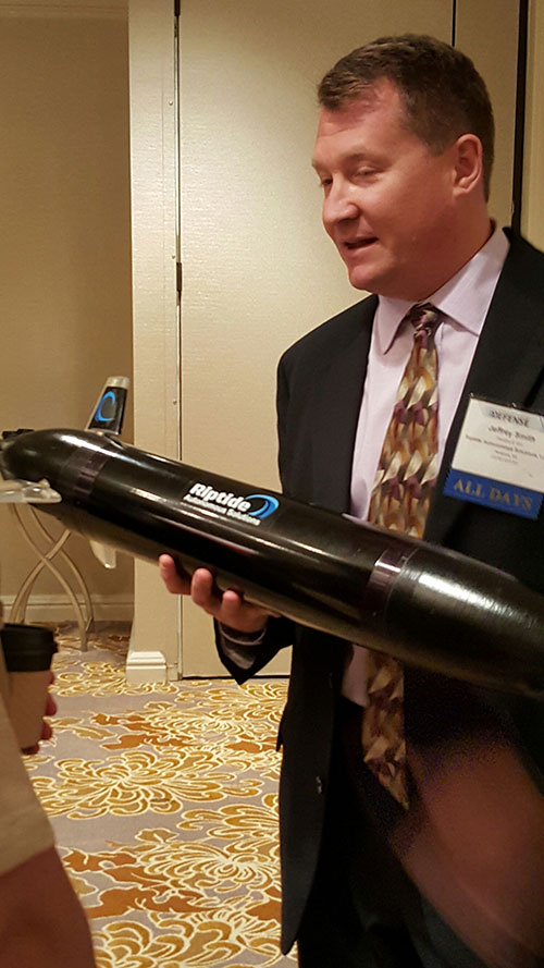 Jeff Smith, president and CEO of Riptide Autonomous Solutions, holds an unmanned undersea vehicle that has GPS sensors and antenna.