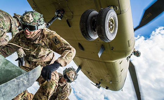 From his side window, a crew chief relays vital position information back to the CH-47 Chinook pilot as paratroopers hook their pallet of equipment to the underside of the helicopter during sling load and air operations training. (Photo: U.S. Army/Maj. Robert Fellingham)