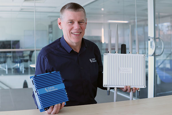 CEO Paul Gray displays the MK6 OBU (left) and RSU. (Photo: Cohda Wireless)