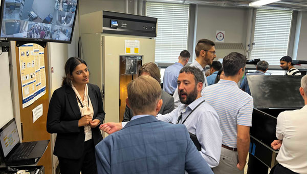 4. The top screen showing the hydrogen maser and cesium clocks in an adjacent isolated room used for realization of the timescale for research purposes. Students presenting their work to the USNO and Microchip Inc., visitors. (Photo: University of Alabama, Tuscaloosa)