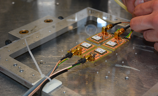 The Astrocast CubeSat's four u-blox receiver modules mounted on an acrylic glass to be placed into a proton radiation beam at the Paul Scherrer Institute in Switzerland. (Photo: ESA)